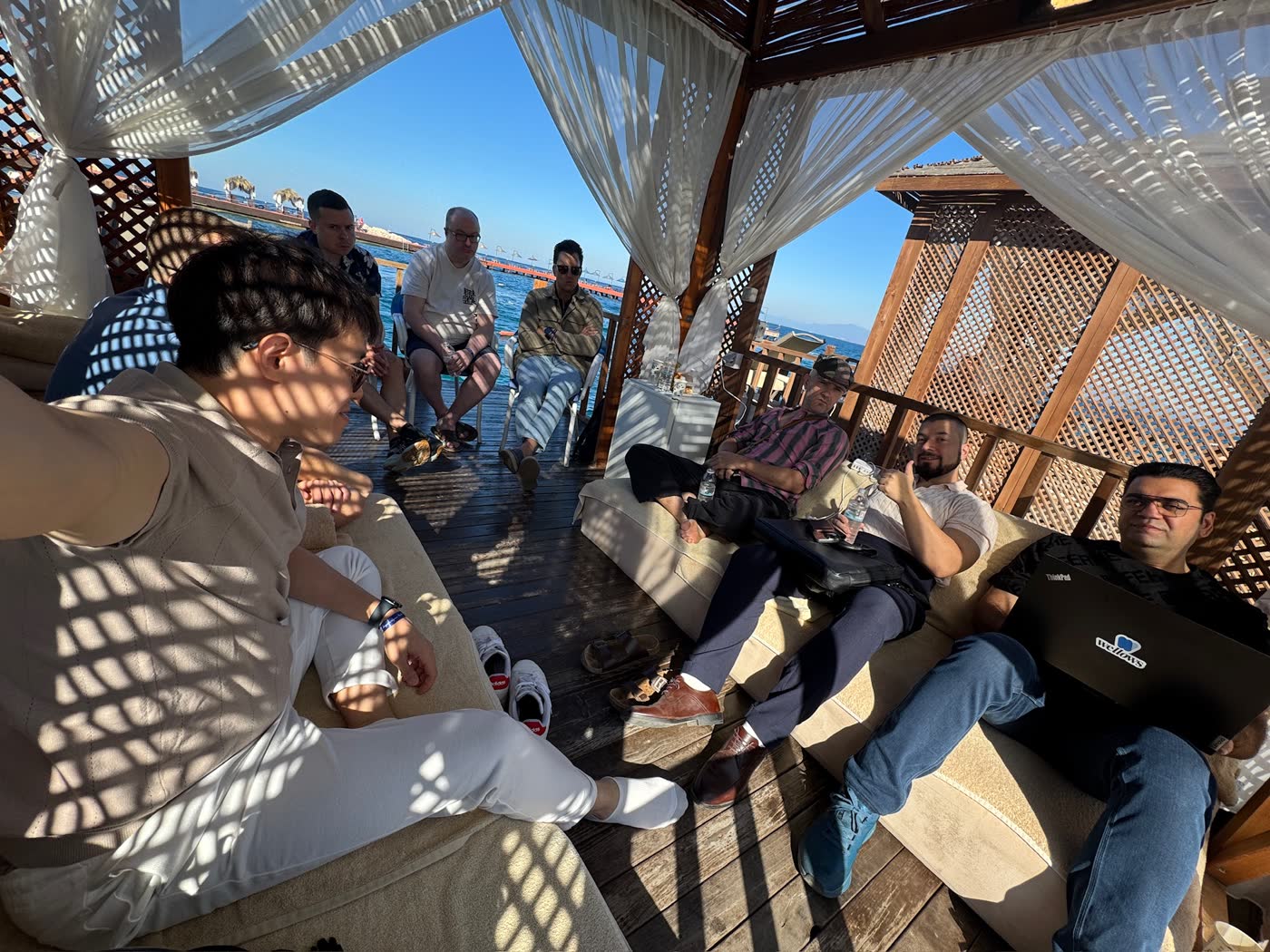 Attendees continuing the conversation in a shaded waterfront cabana